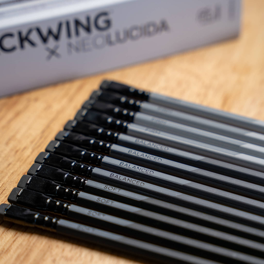 Blackwing Neolucida pencils with black erasers and gray barrels arranged on wooden surface
