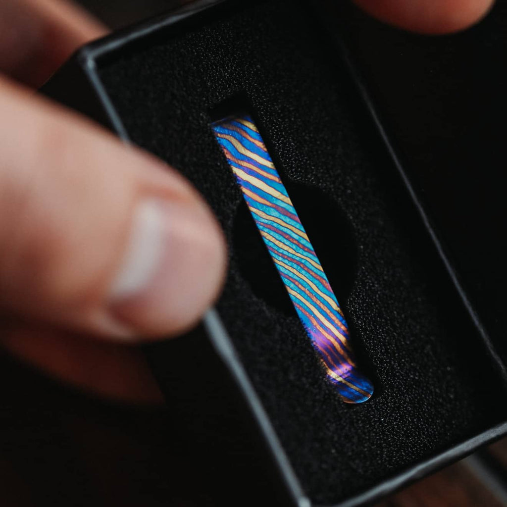 Close-up of a colorful Titanium Damascus pen clip in black foam packaging by Big Idea Design LLC