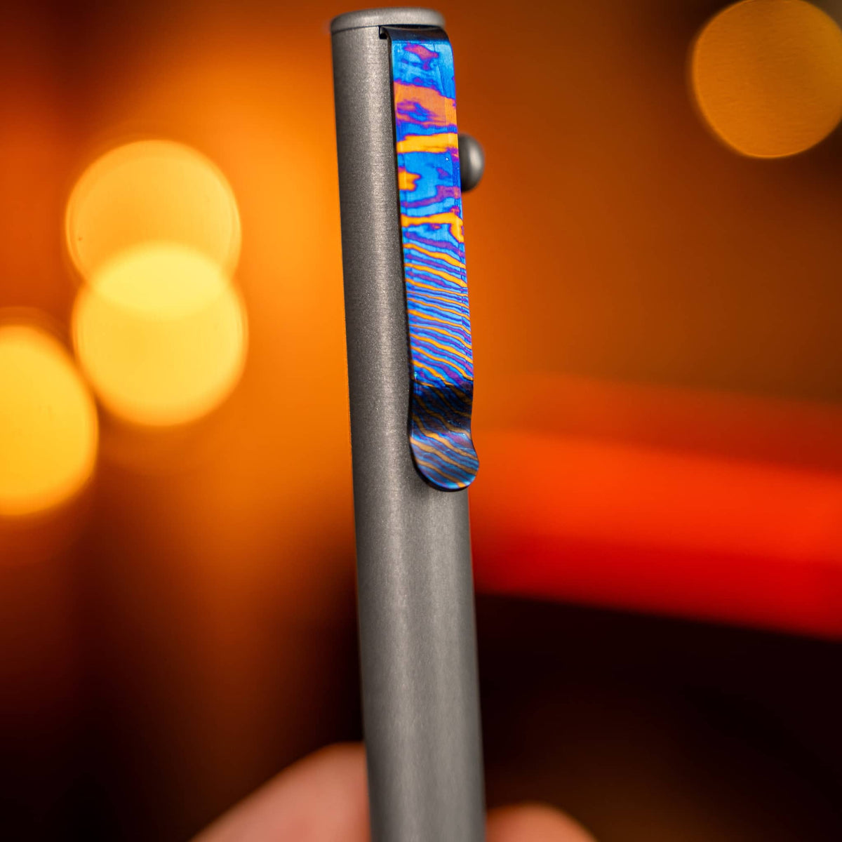 Close-up of a pen with a colorful titanium Damascus pen clip by Big Idea Design LLC in warm lighting