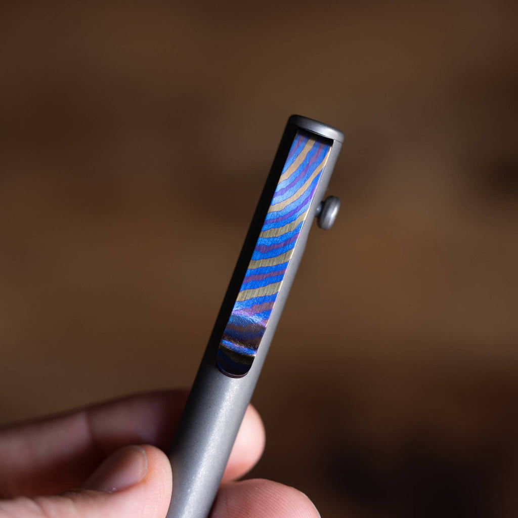 Close-up of a pen featuring a Titanium Damascus pen clip held in hand by Big Idea Design LLC