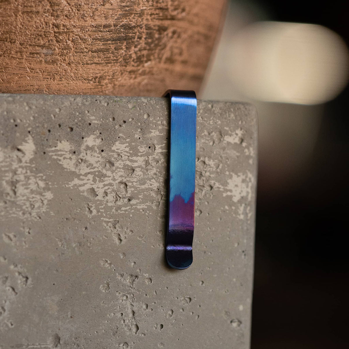 Blue and purple titanium Damascus pen clip attached to a concrete surface by Big Idea Design LLC