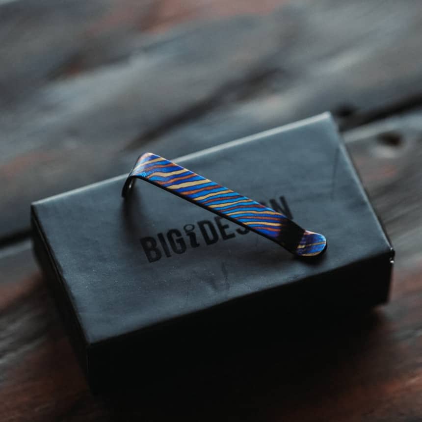 Titanium Damascus pen clip with vibrant blue and gold pattern on Big Idea Design LLC black box